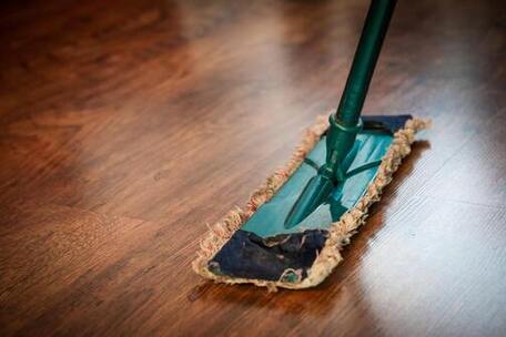 Close up of a dry, dust mop cleaning a hardwood floor.