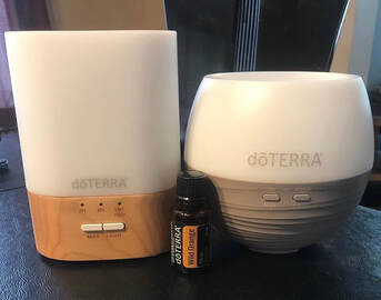 Two doTERRA diffusers with wild orange essential oil bottle.